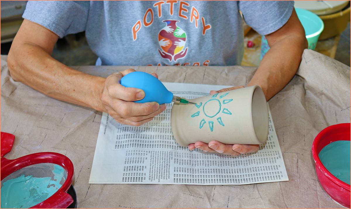 an image of a potter slip trailing a cup with underglaze