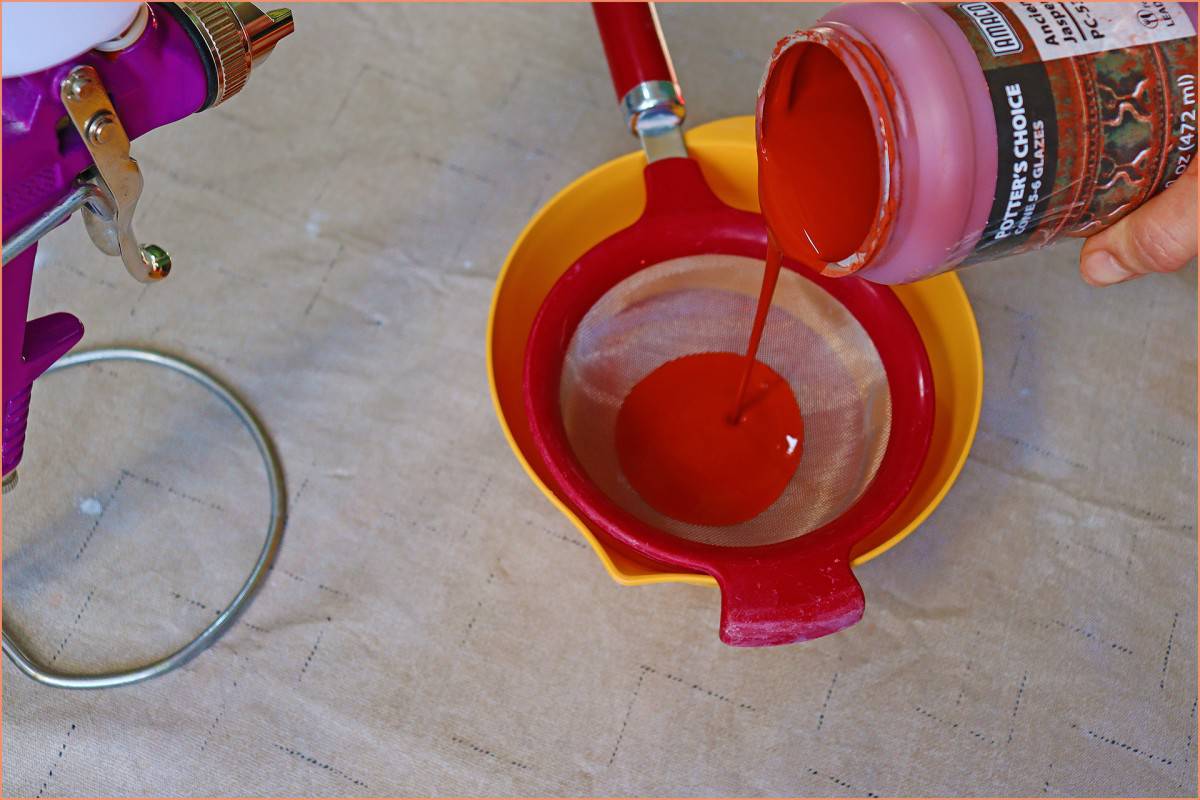 a picture of a potter pouring glaze through strainer