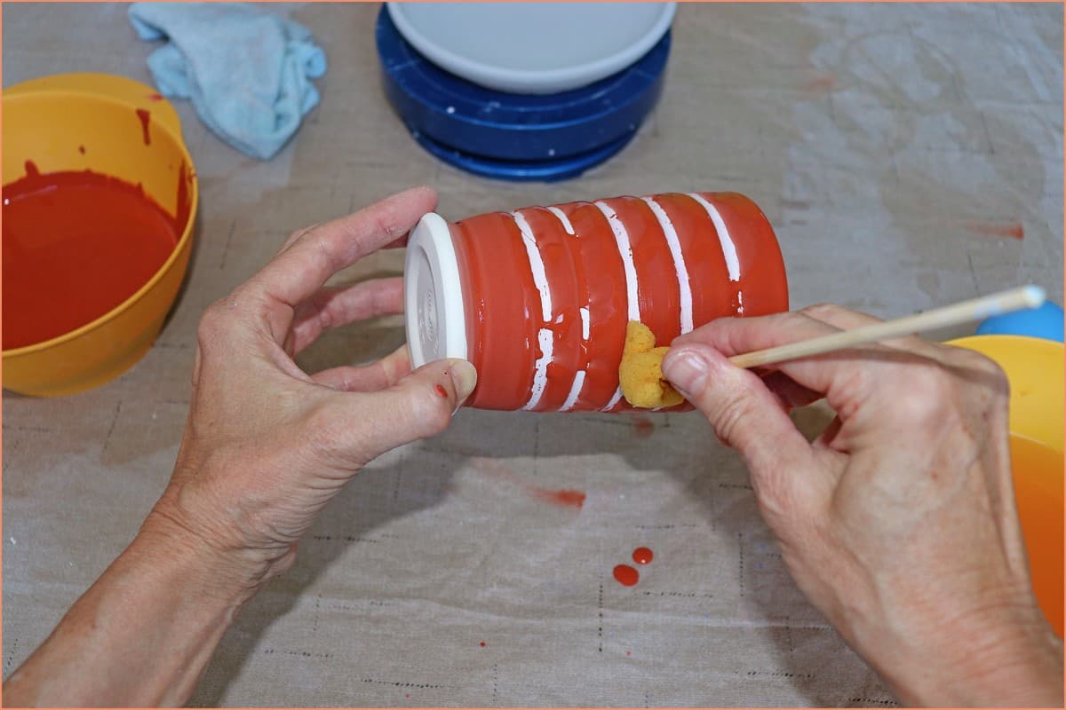a picture of a potter wiping off glaze wax resist area