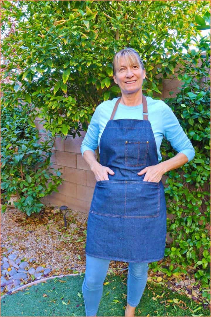 a female standing up and modeling a meychin  blue adjustable denim apron
