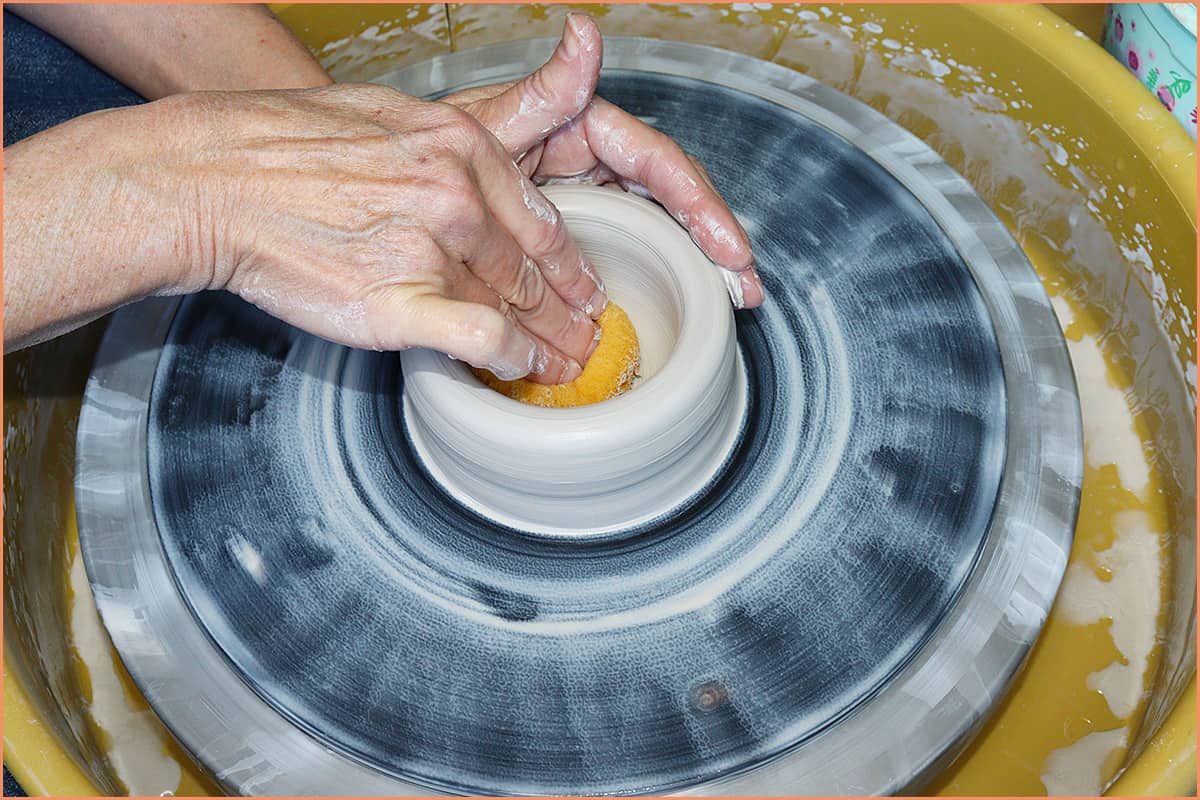 an image of a potter compressing the bottom of clay