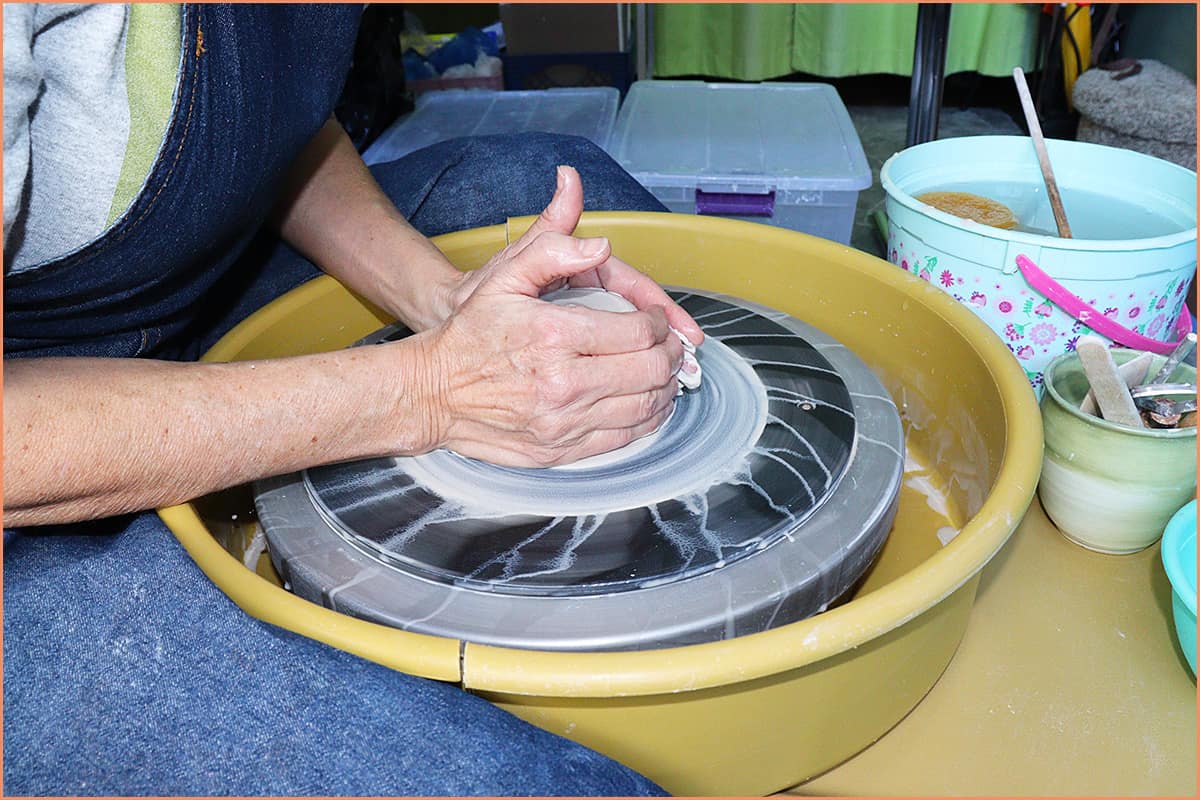 an image of a potter squeezing clay with both hands