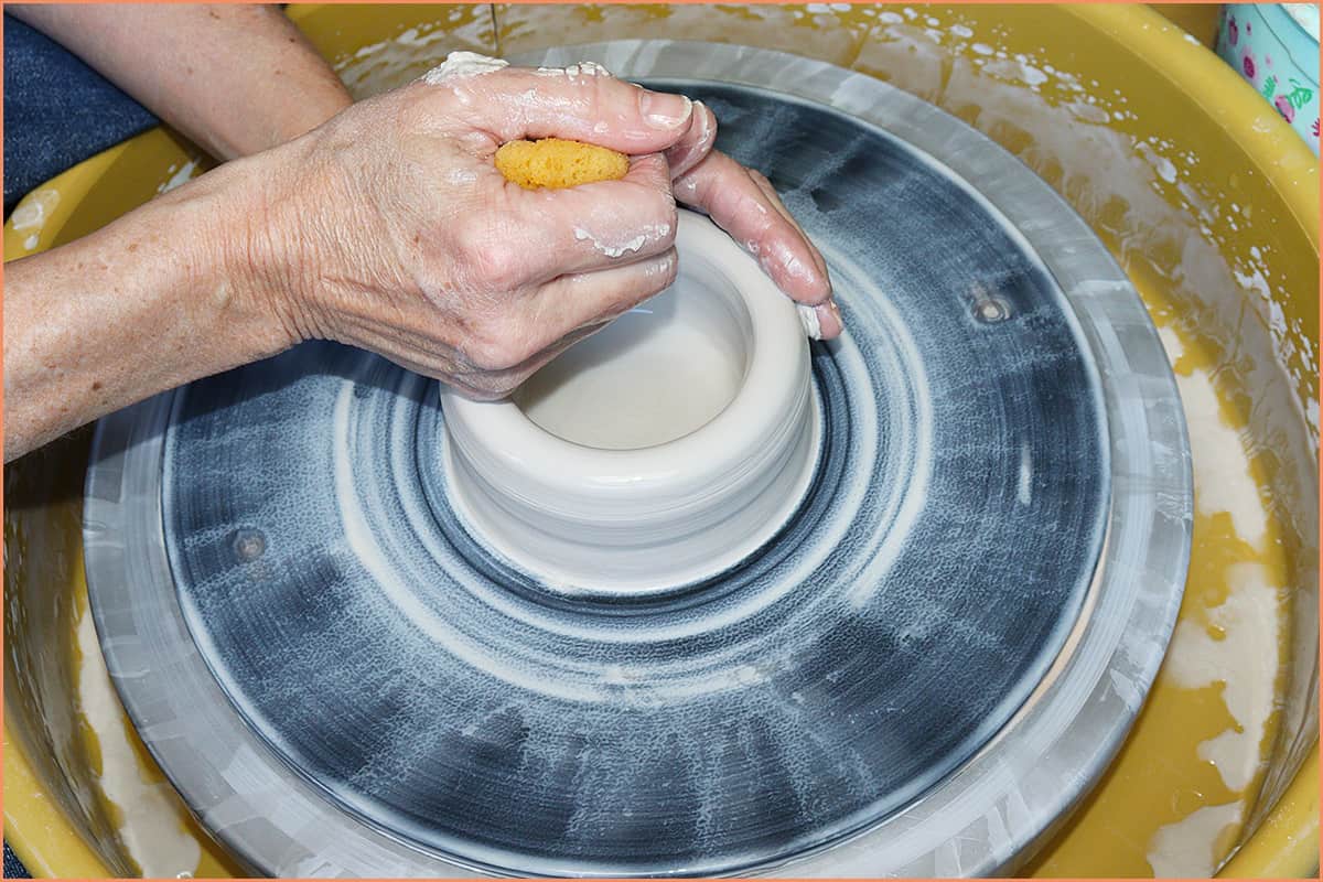 an image of a potter squeezing water on clay