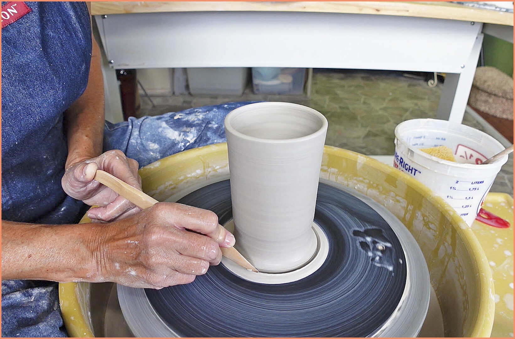 an image of a potter making a lip on a clay pot with a modeling tool