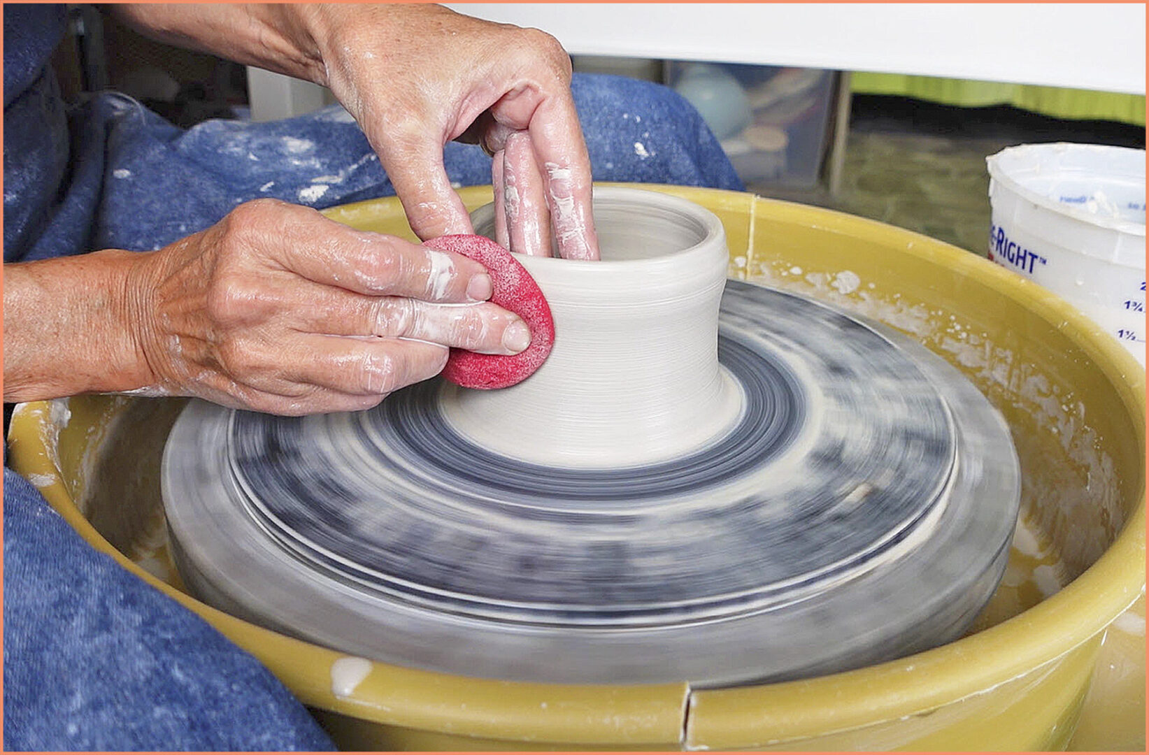 an image of a potter pulling up the walls using a sponge